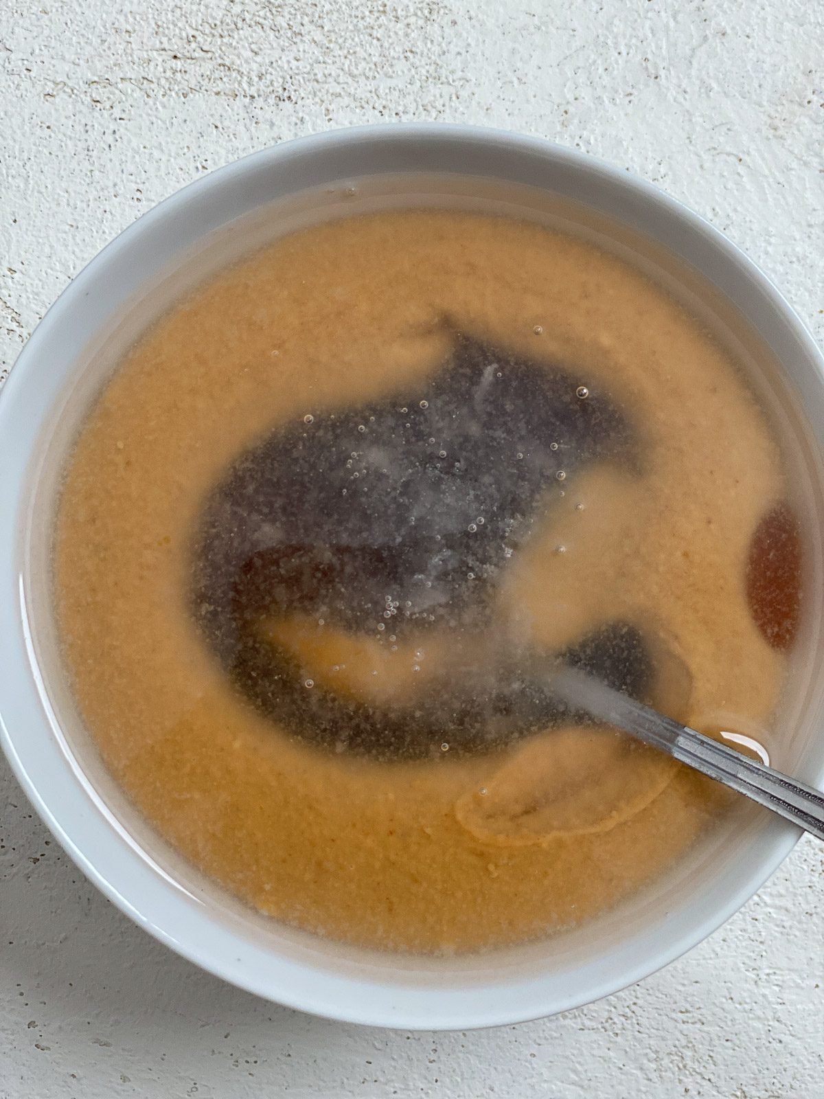 process of mixing ingredients for Simple Vegan Caramel in a white bowl