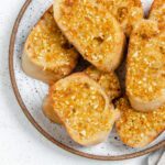 several pieces of completed Vegan Air Fryer Garlic Bread on a white plate