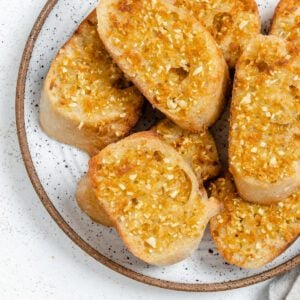 several pieces of completed Vegan Air Fryer Garlic Bread on a white plate