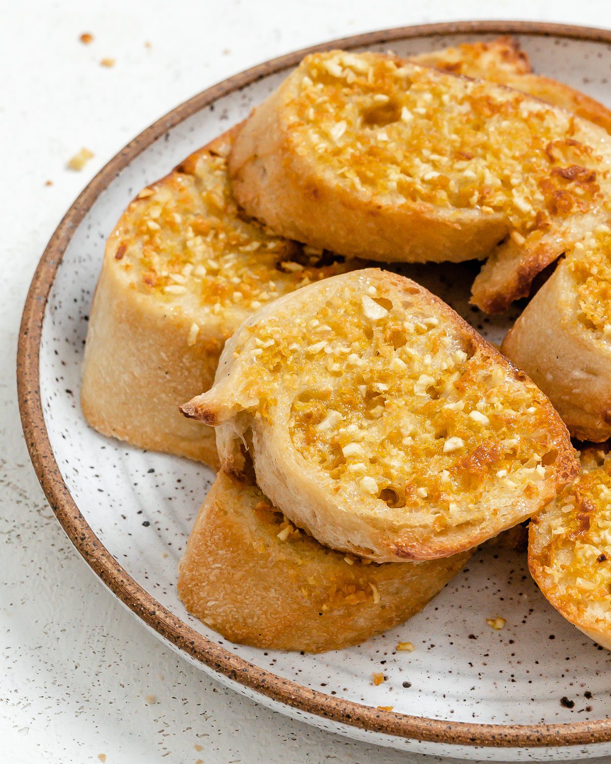 several pieces of completed Vegan Air Fryer Garlic Bread on a white plate