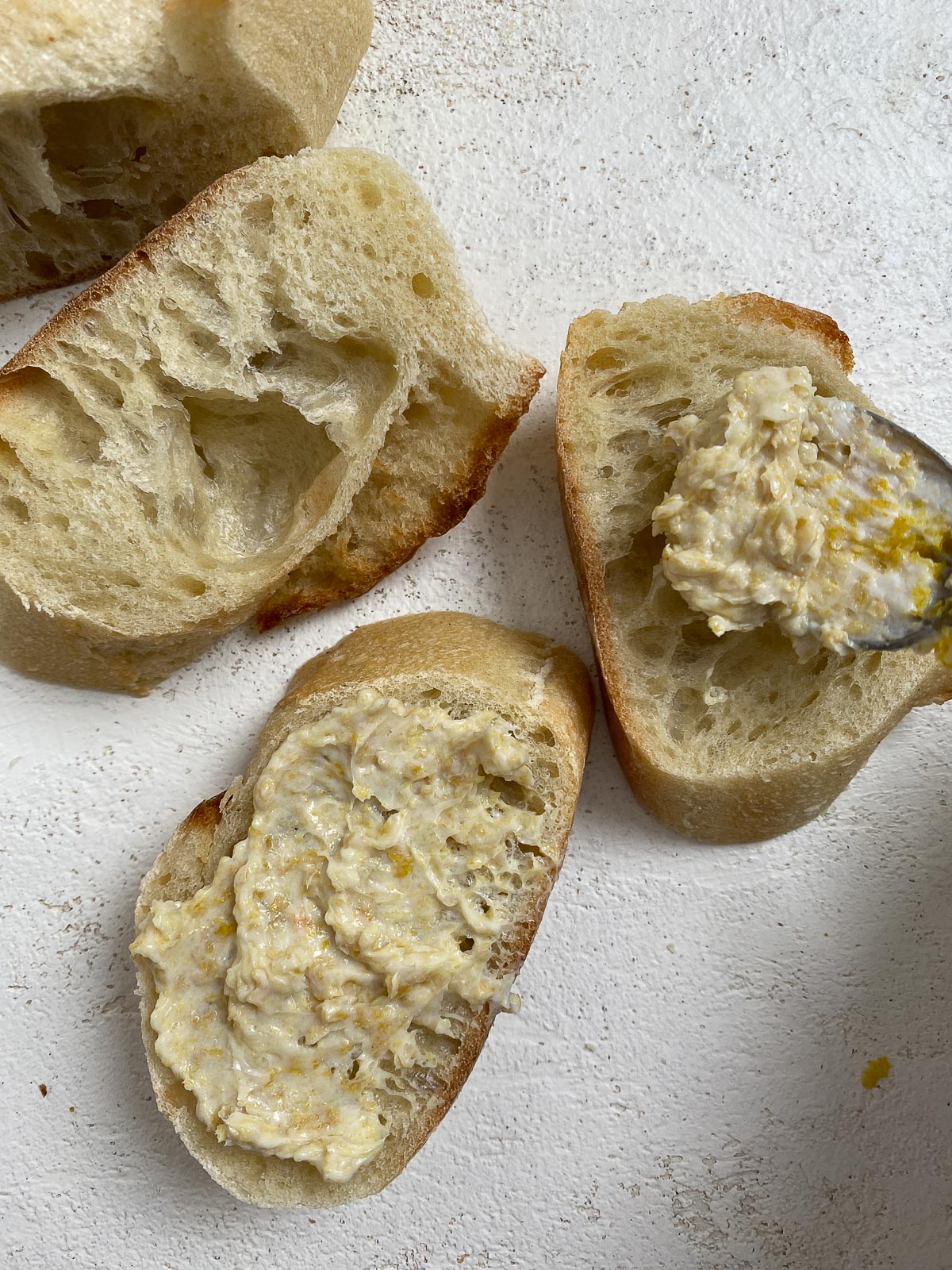process of spreading garlic bread mixture on three pieces of sliced bread