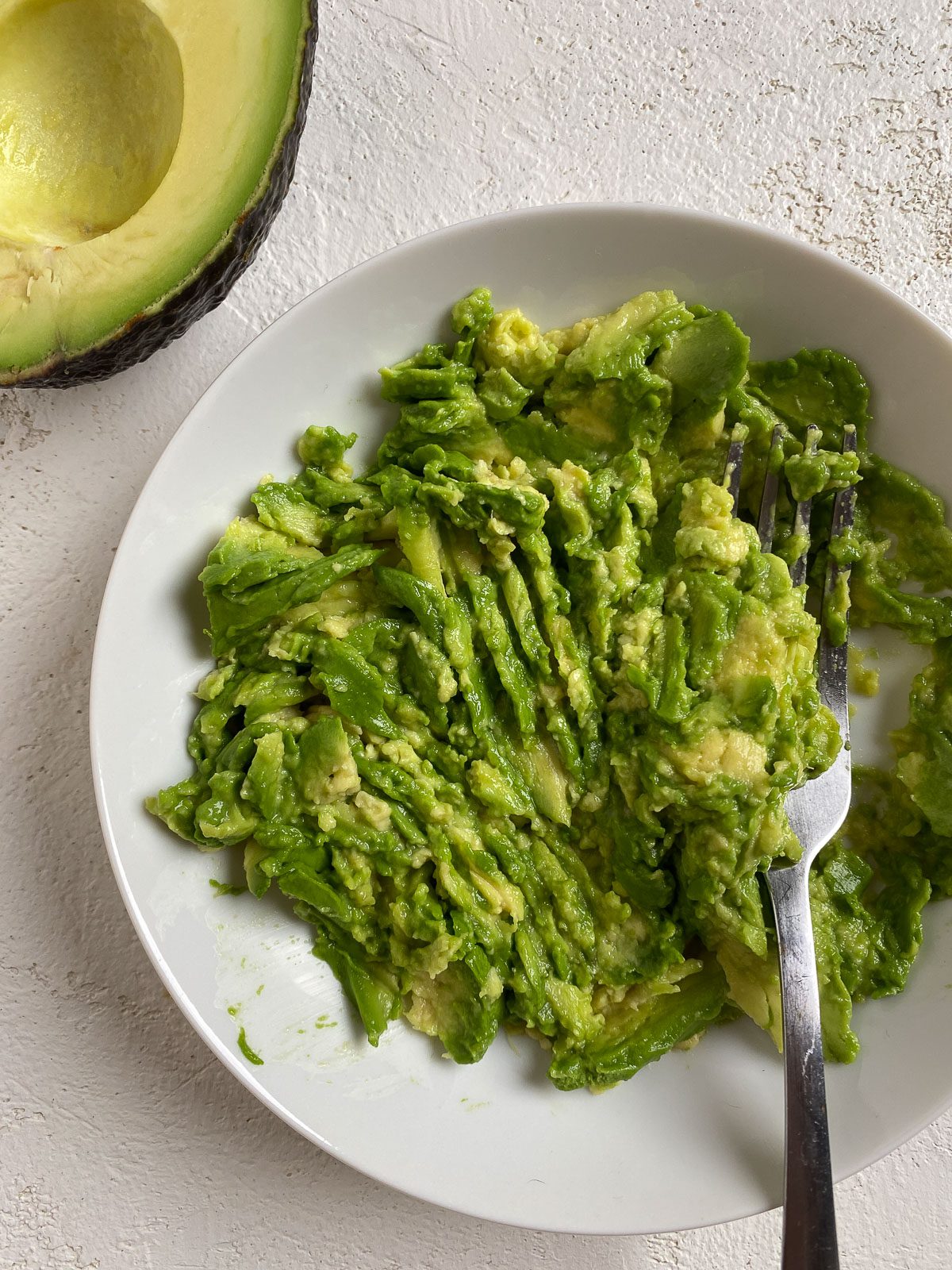 process shot of smashed avocado on a white plate