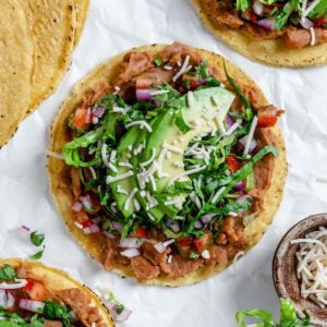 completed Vegan Bean Tostadas with tostadas in the background against a light surface