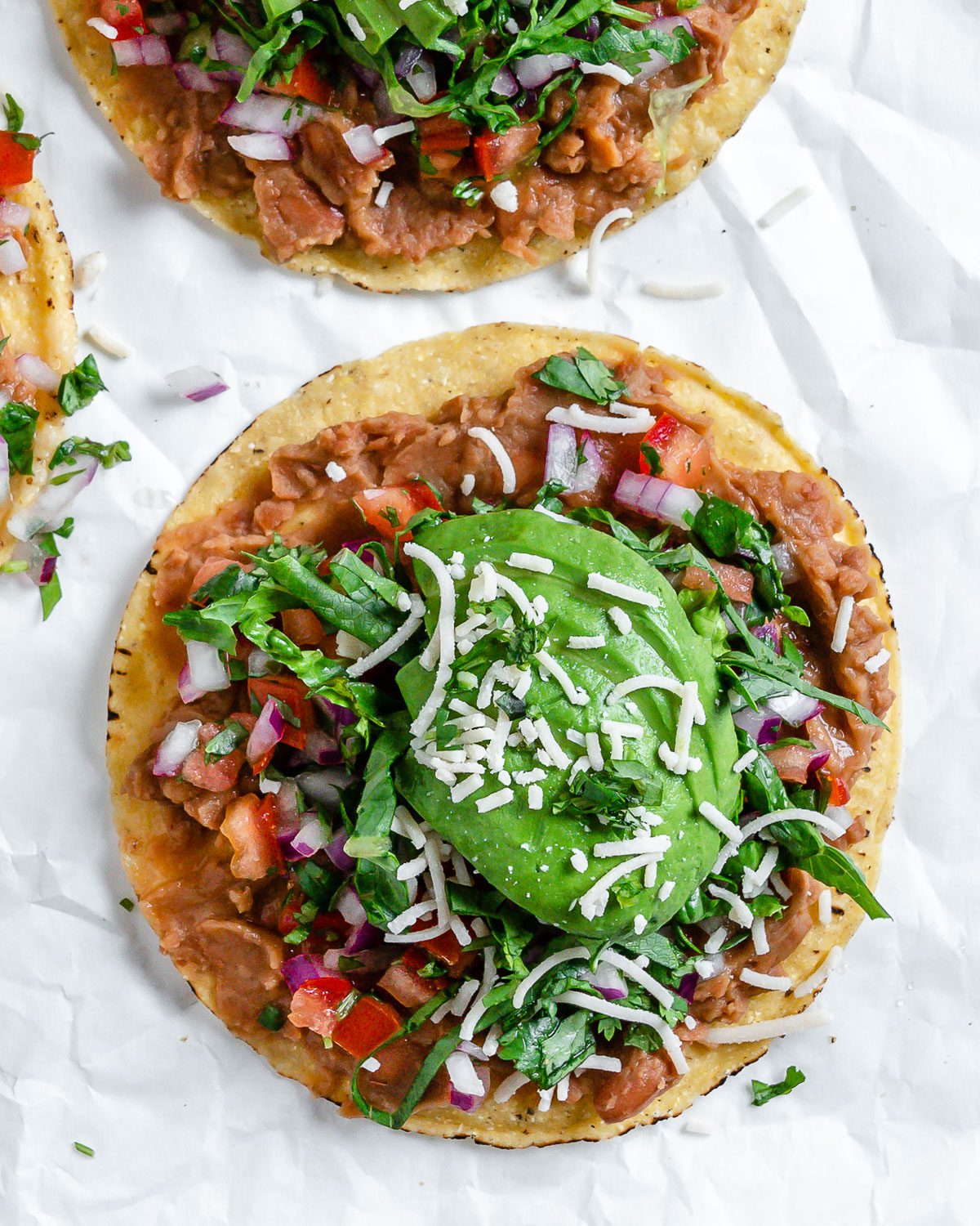 completed Vegan Bean Tostadas with tostadas in the background against a light surface