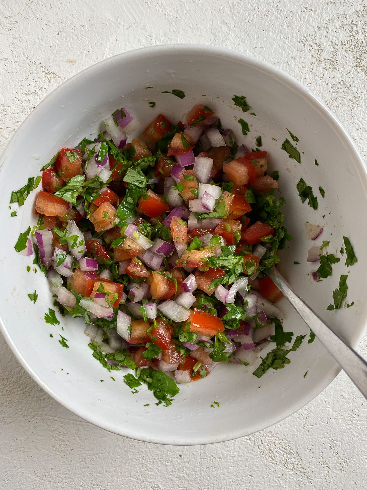 post mixing veggies for Vegan Bean Tostadas in a white bowl