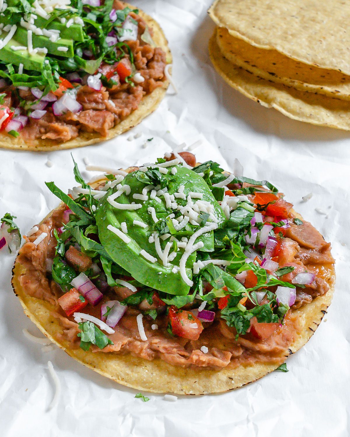 completed Vegan Bean Tostadas with tostadas in the background against a light surface