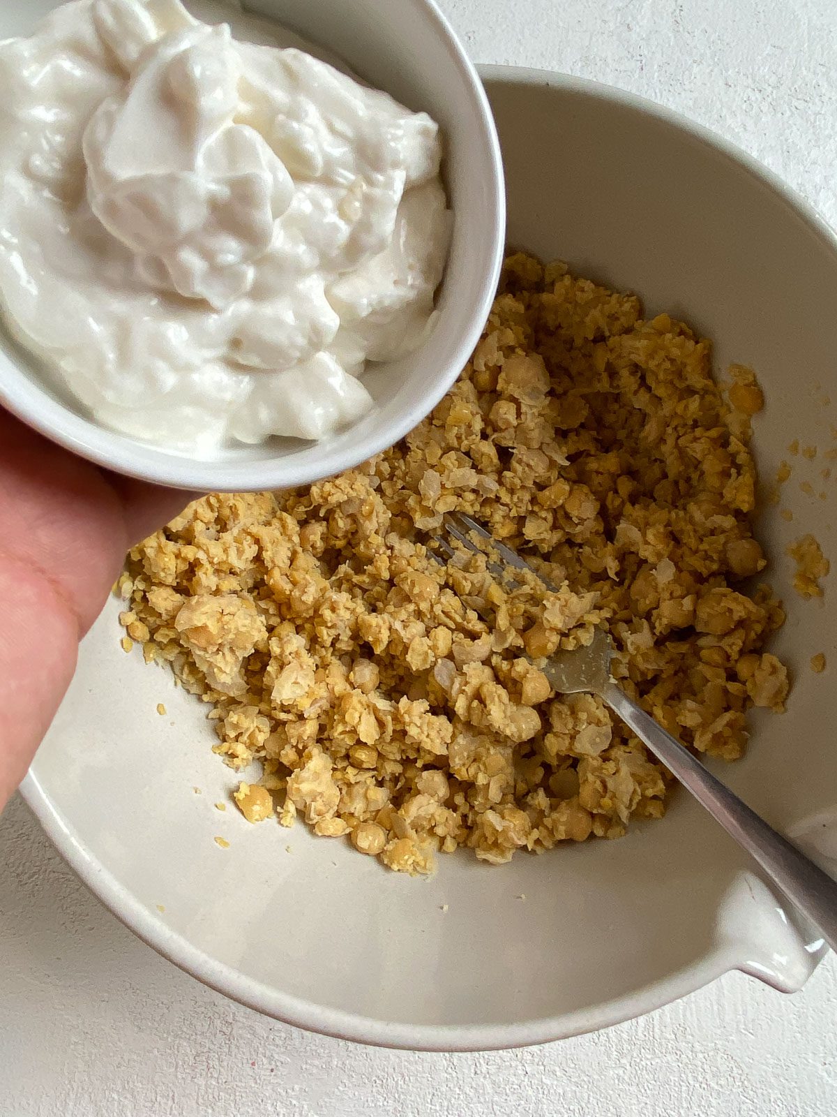 process shot of adding vegan mayo to bowl of mashed potatoes