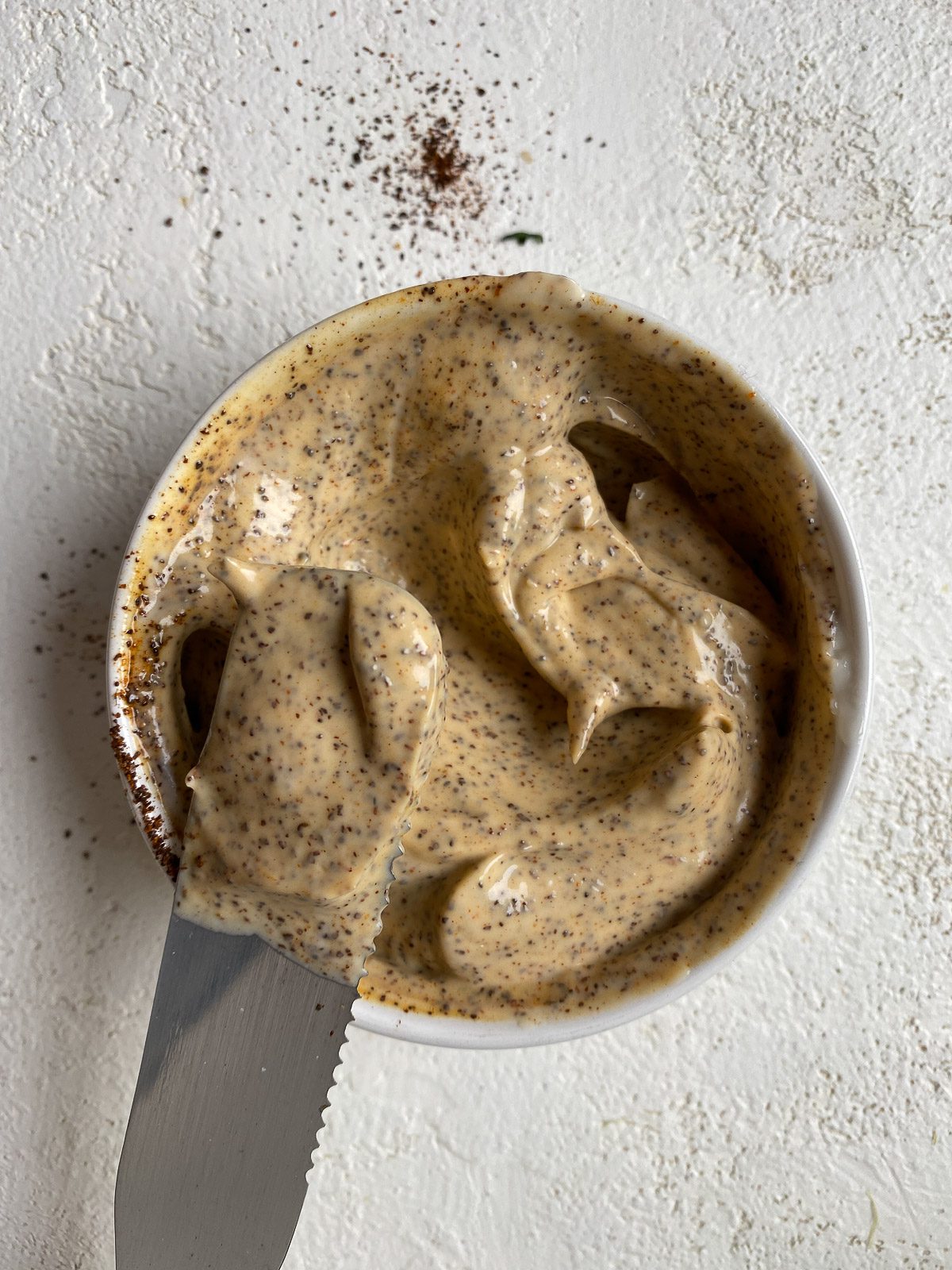 Process shot of mixing vegan elote ingredients in a small bowl against a light surface.