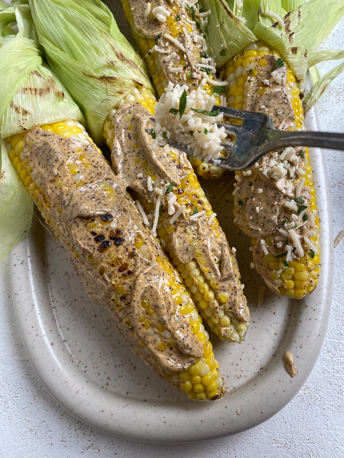 Process of brushing vegan mixture onto cobs of corn.