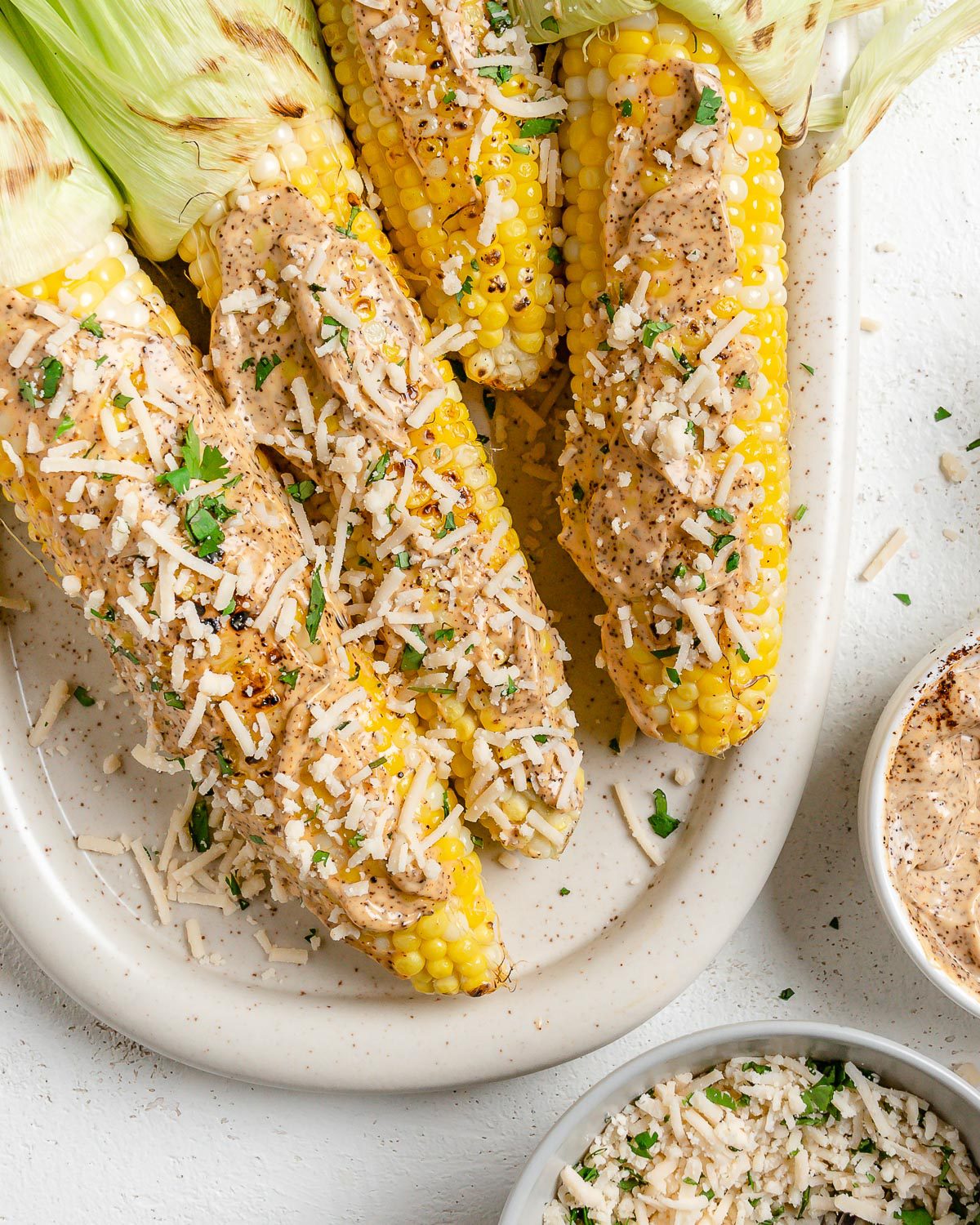 Several completed Vegan Elote on a light dish against a light surface.