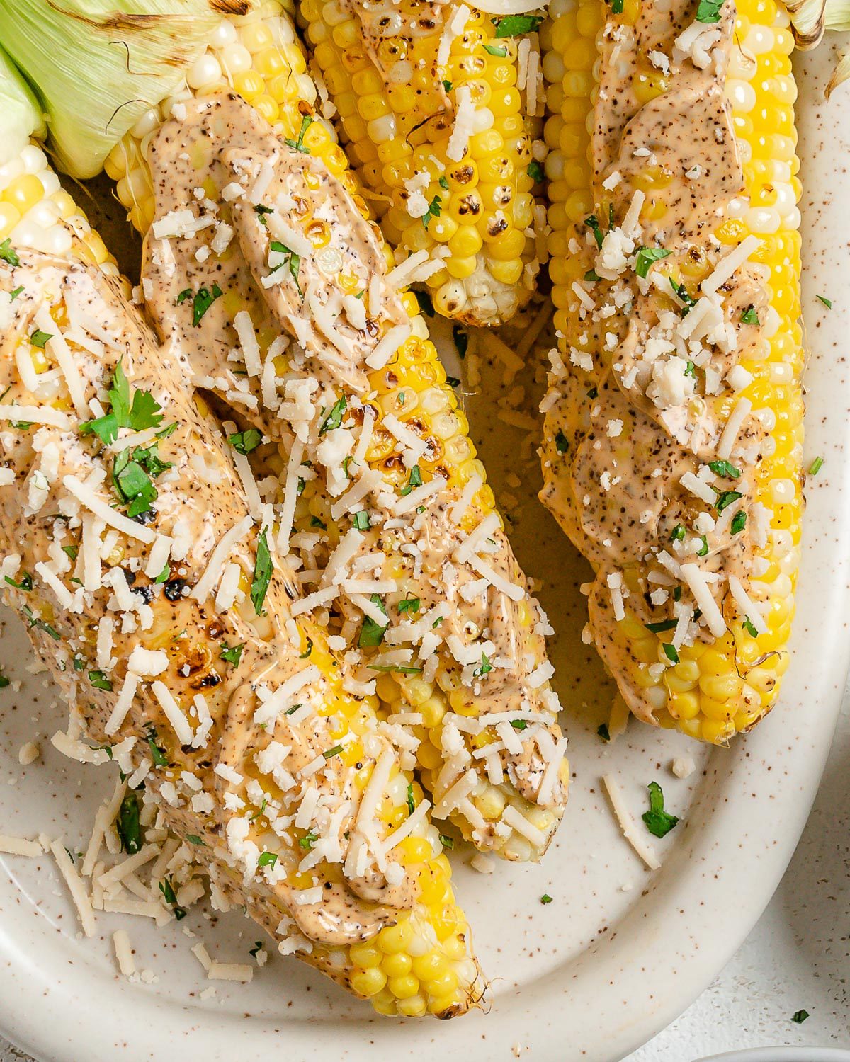 Several completed Vegan Elote on a light dish against a light surface.