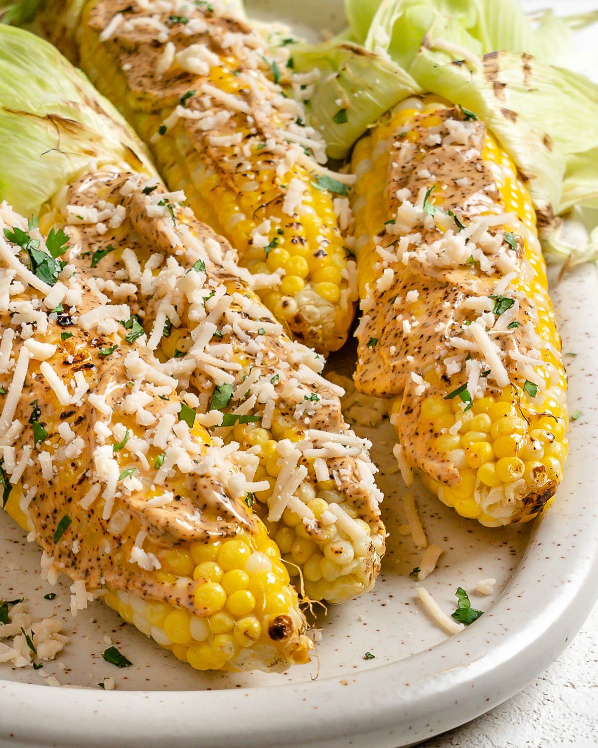 Several completed Vegan Elote on a light dish against a light surface.