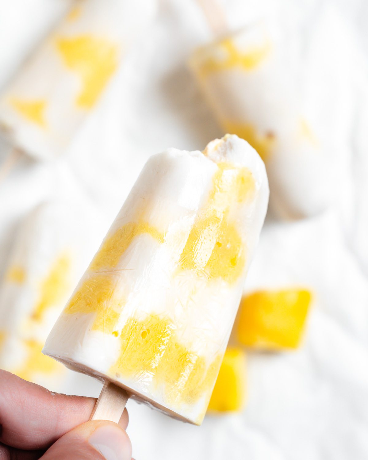 several completed Vegan Mango Popsicles against a white surface