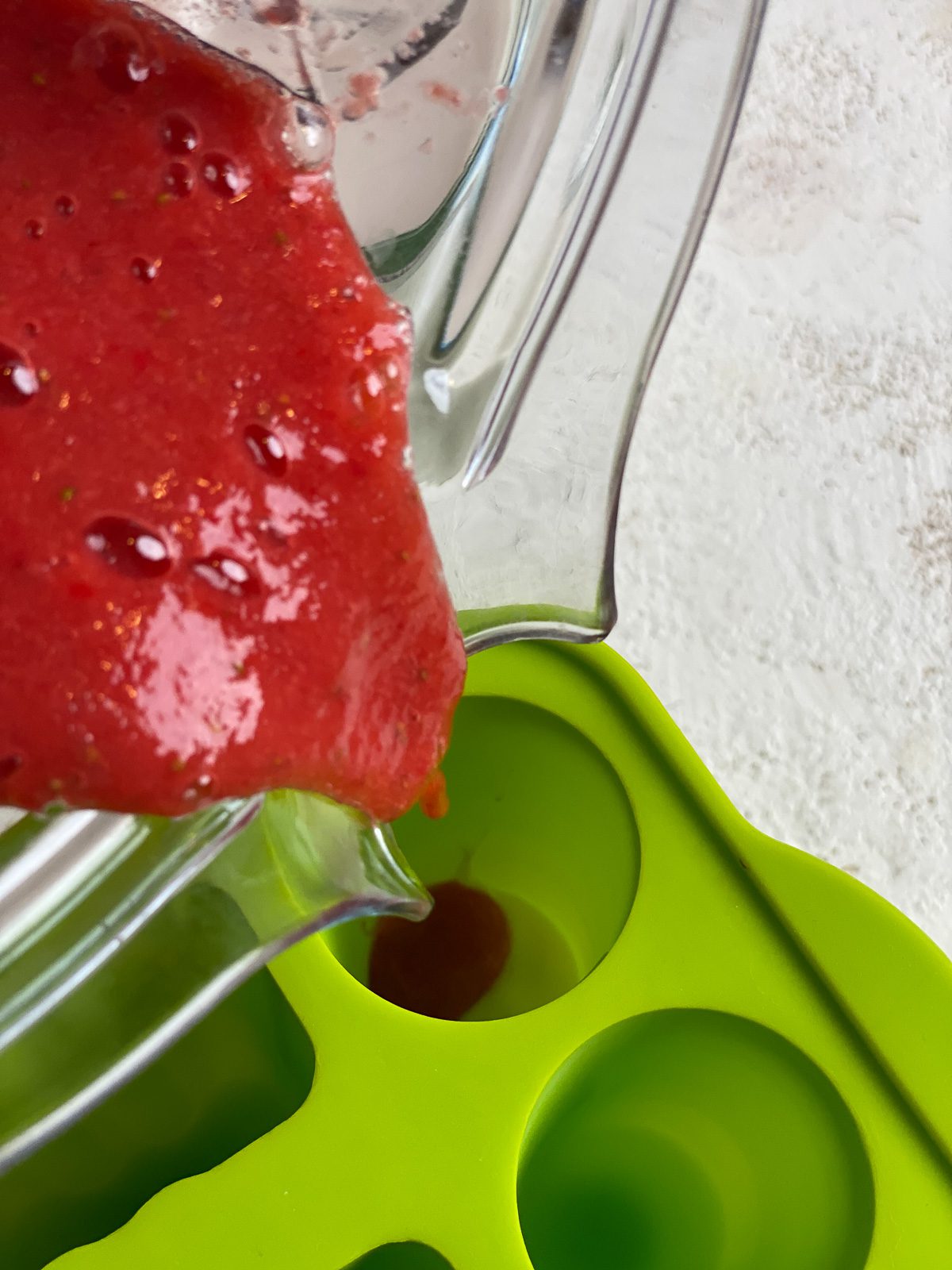 process of adding strawberry mixture to popsicle molds