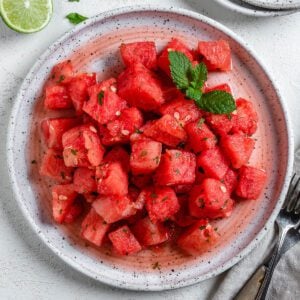 completed Vegan Watermelon Lime Mint Salad on a white plate against a white surface
