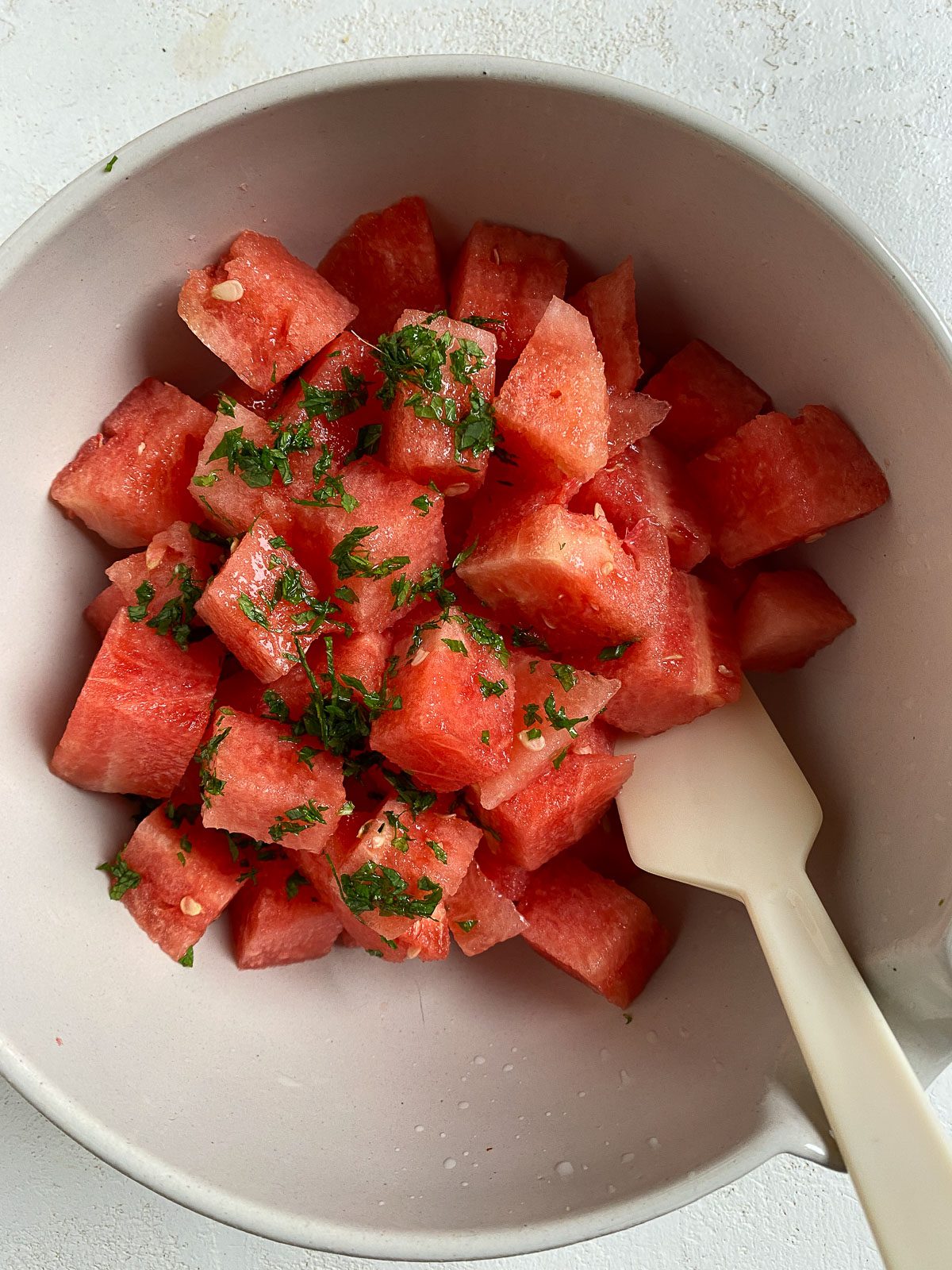 process of mixing ingredients for Vegan Watermelon Lime Mint Salad in a bowl