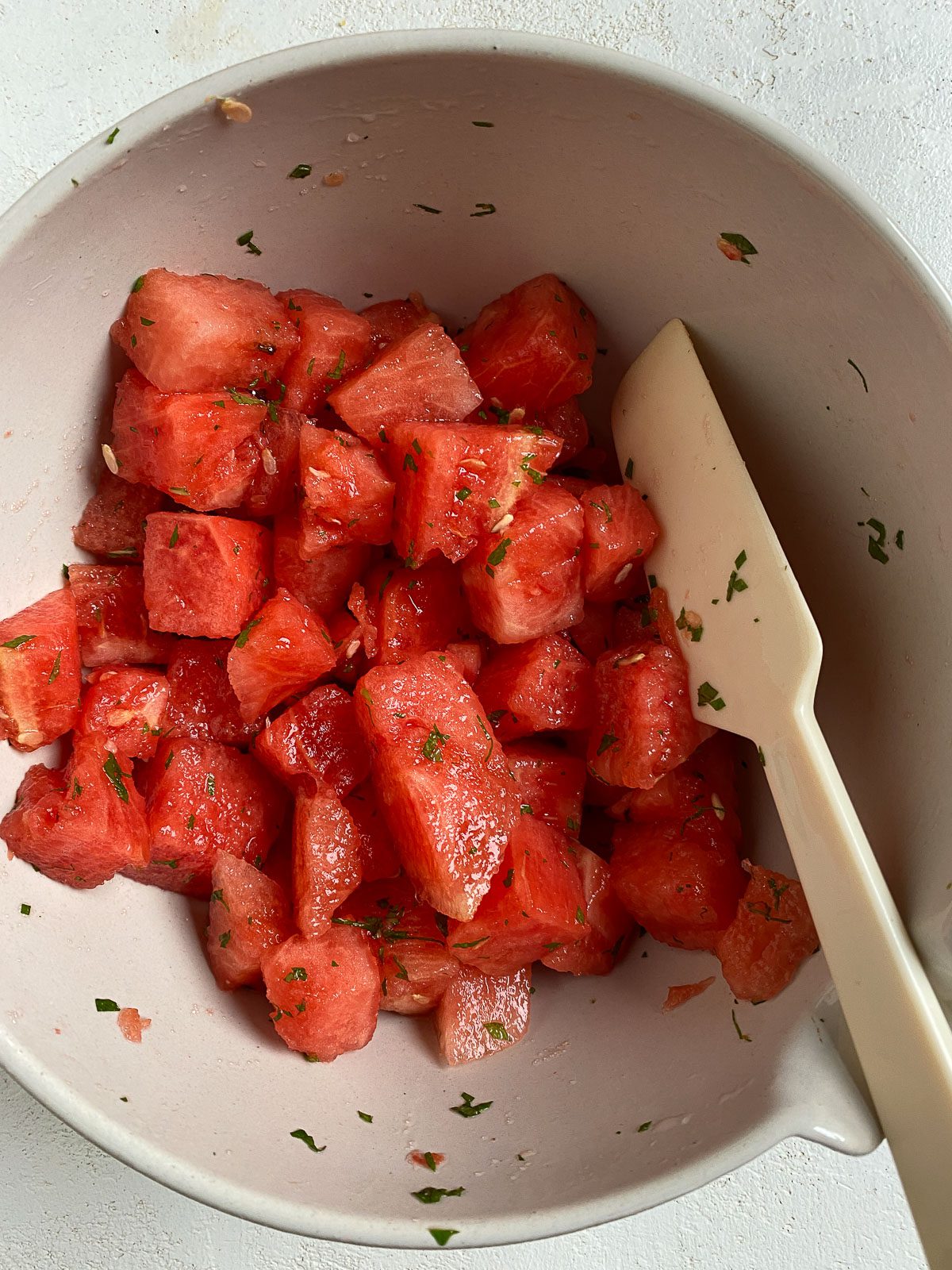 process of mixing ingredients for Vegan Watermelon Lime Mint Salad in a bowl