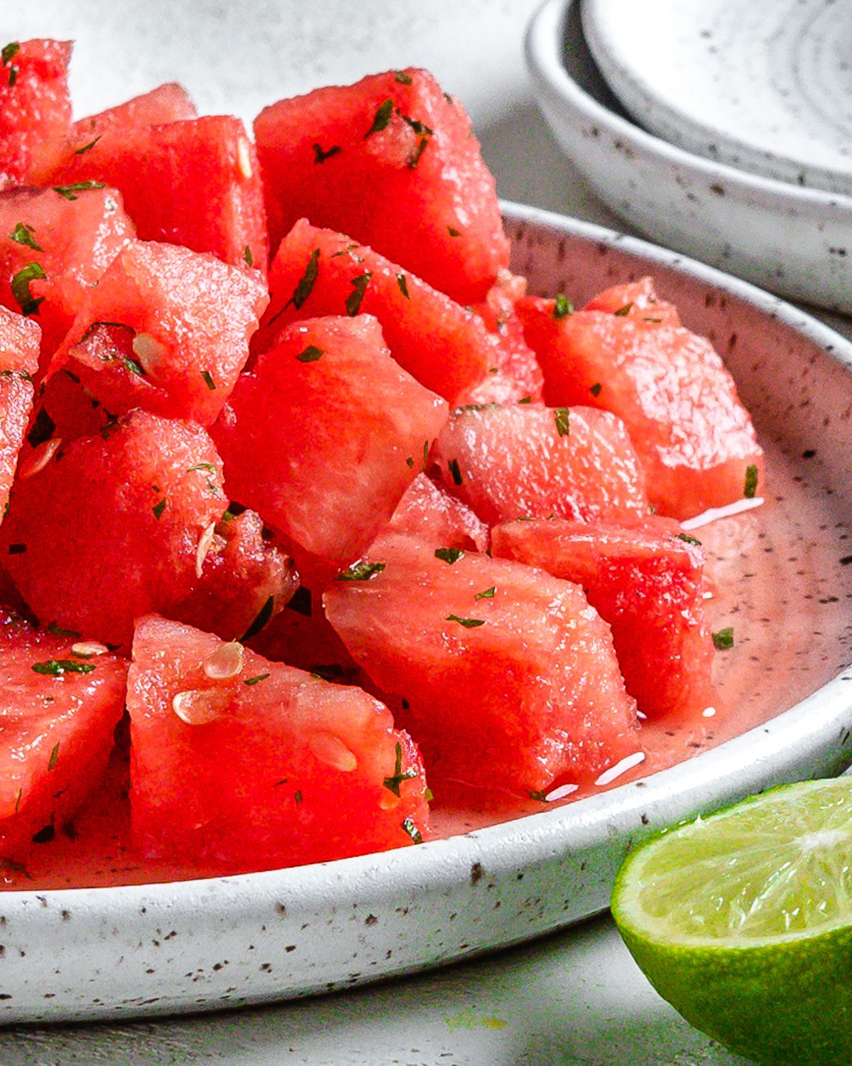 completed Vegan Watermelon Lime Mint Salad on a white plate against a white surface