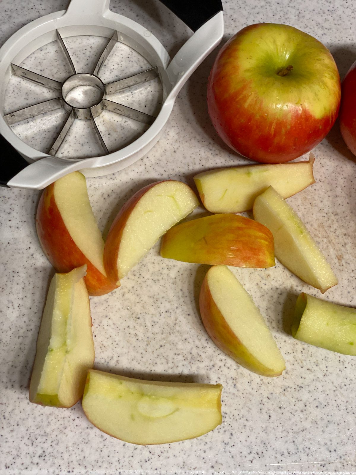 sliced apples and a whole apple alongside an apple slicer