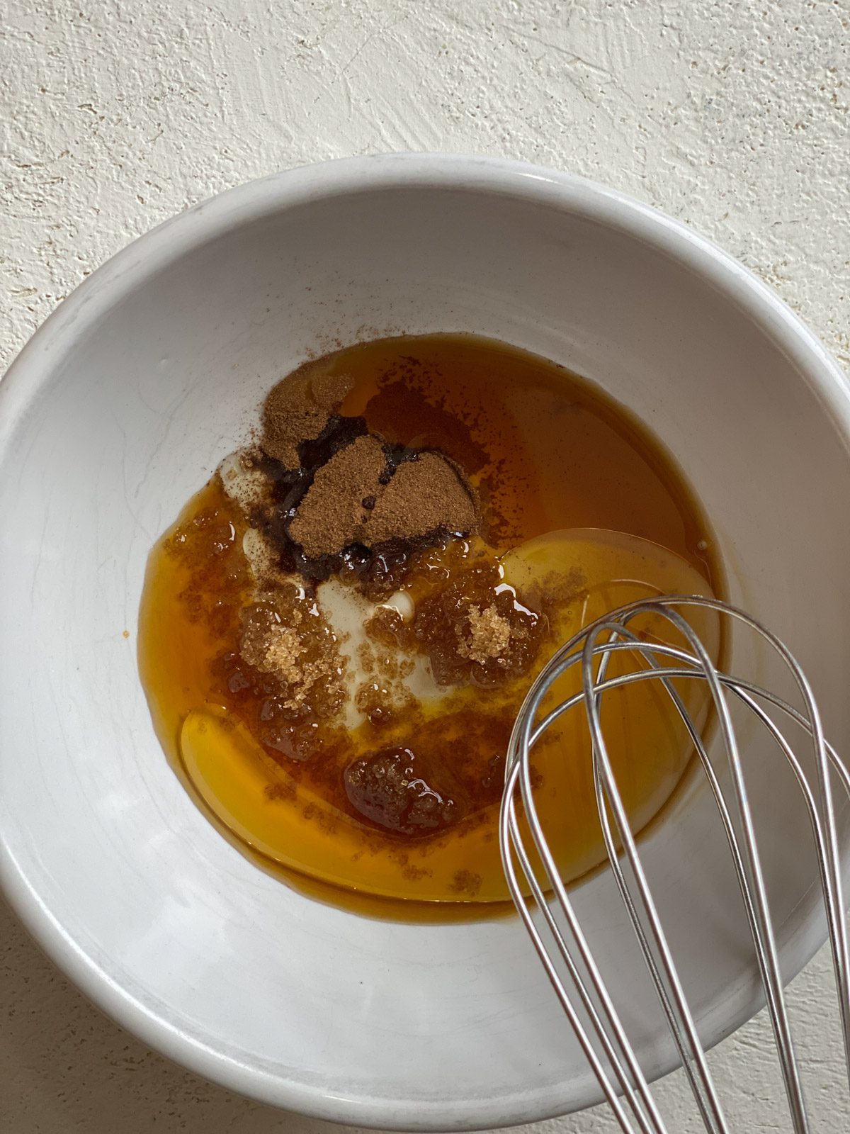 process of mixing air fryer apple topping ingredients in a white bowl