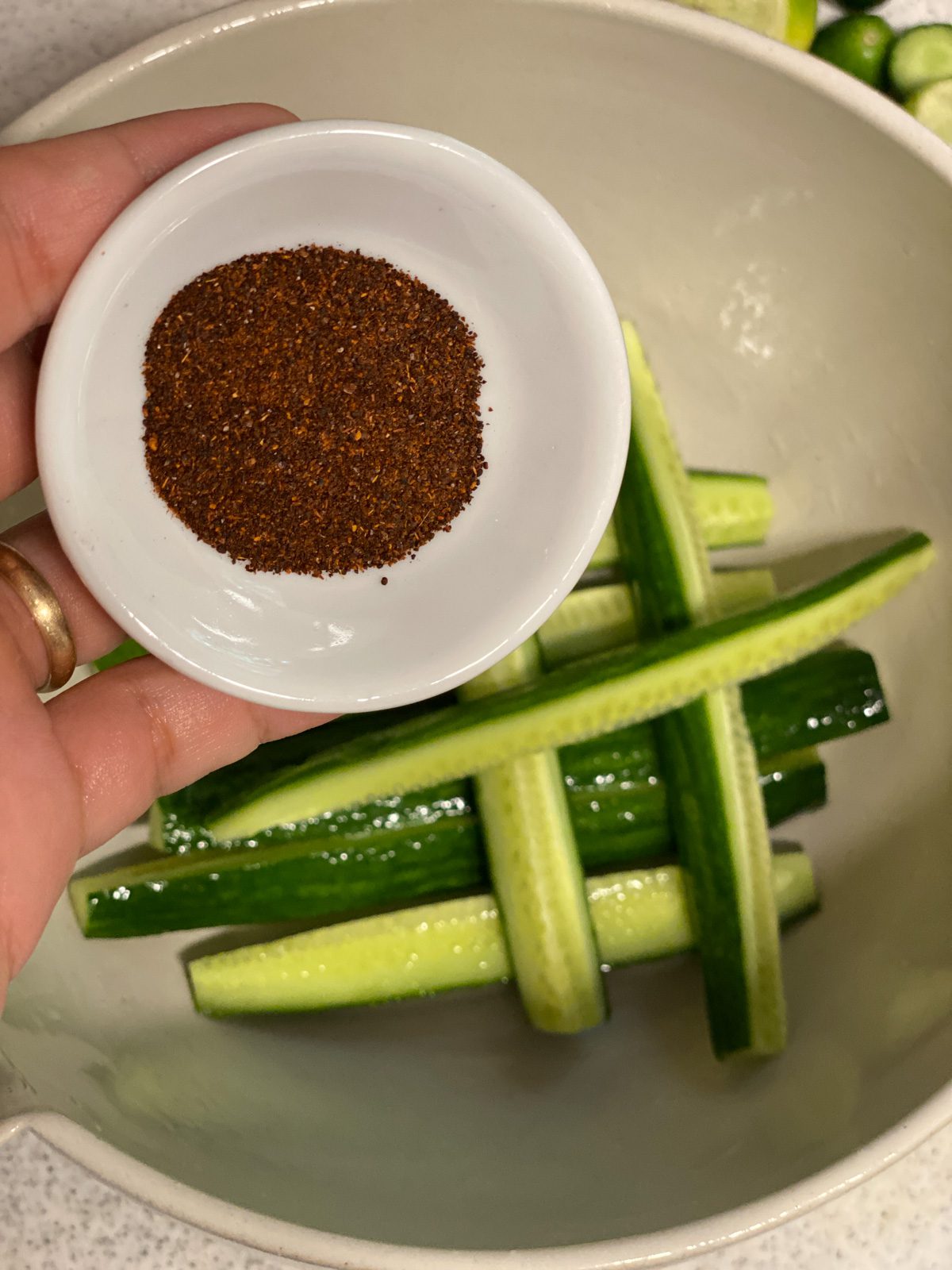 a bowl of tajin shown above a bowl of sliced cucumbers