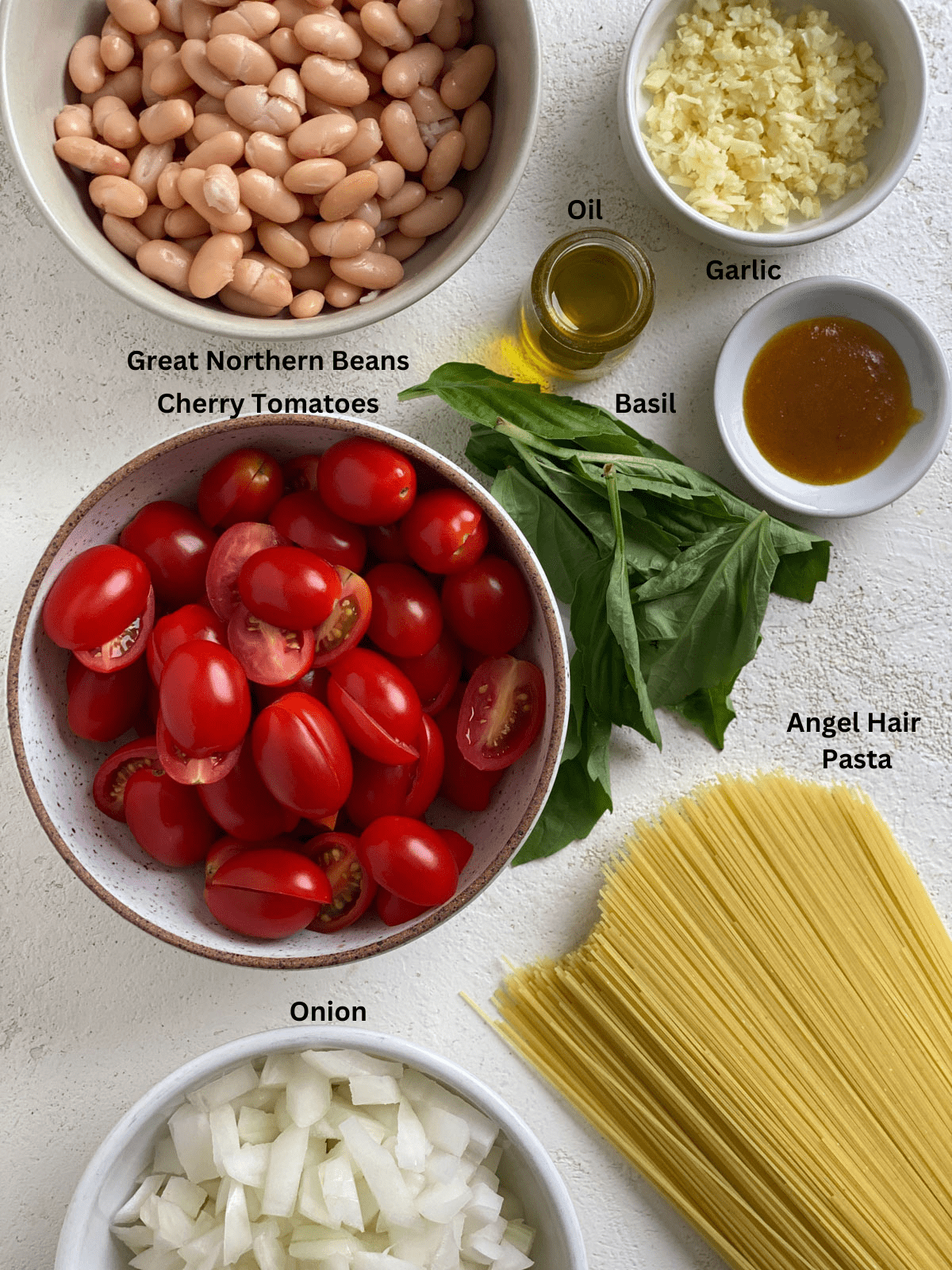 Ingredients for Vegan Tomato Basil Angel Hair Pasta measured out against a white surface.