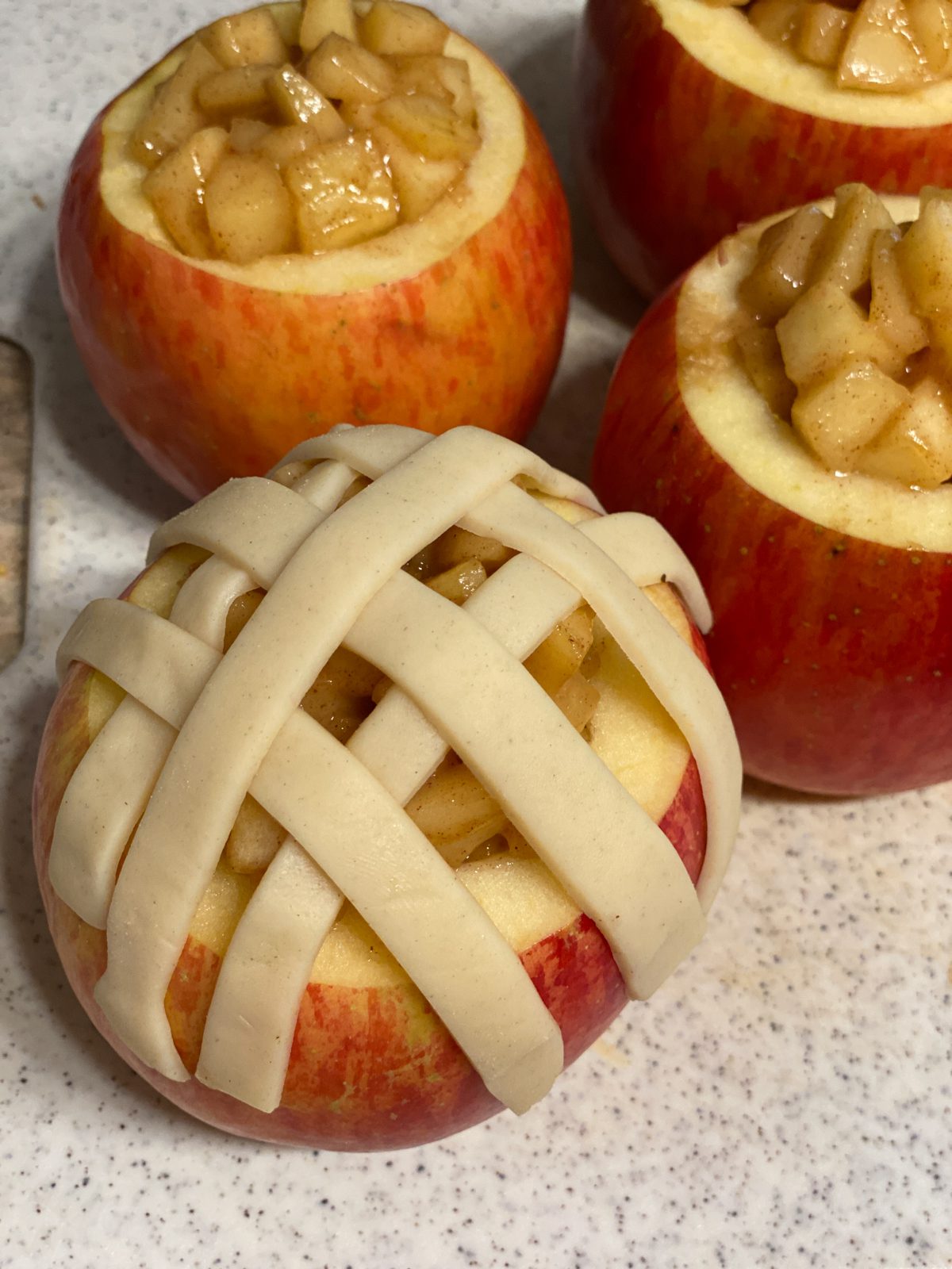 Process shot post putting strips of pie crust on unbaked apple.