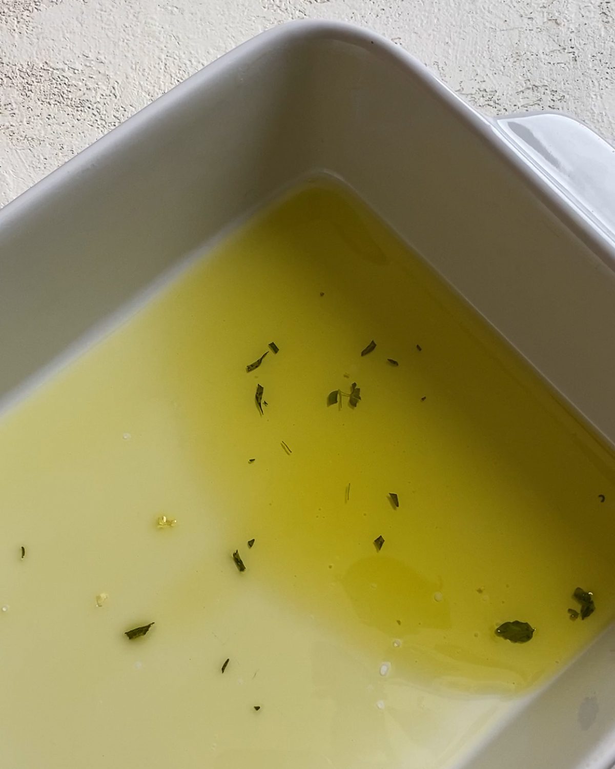 process of adding oil and herb mixture into baking pan