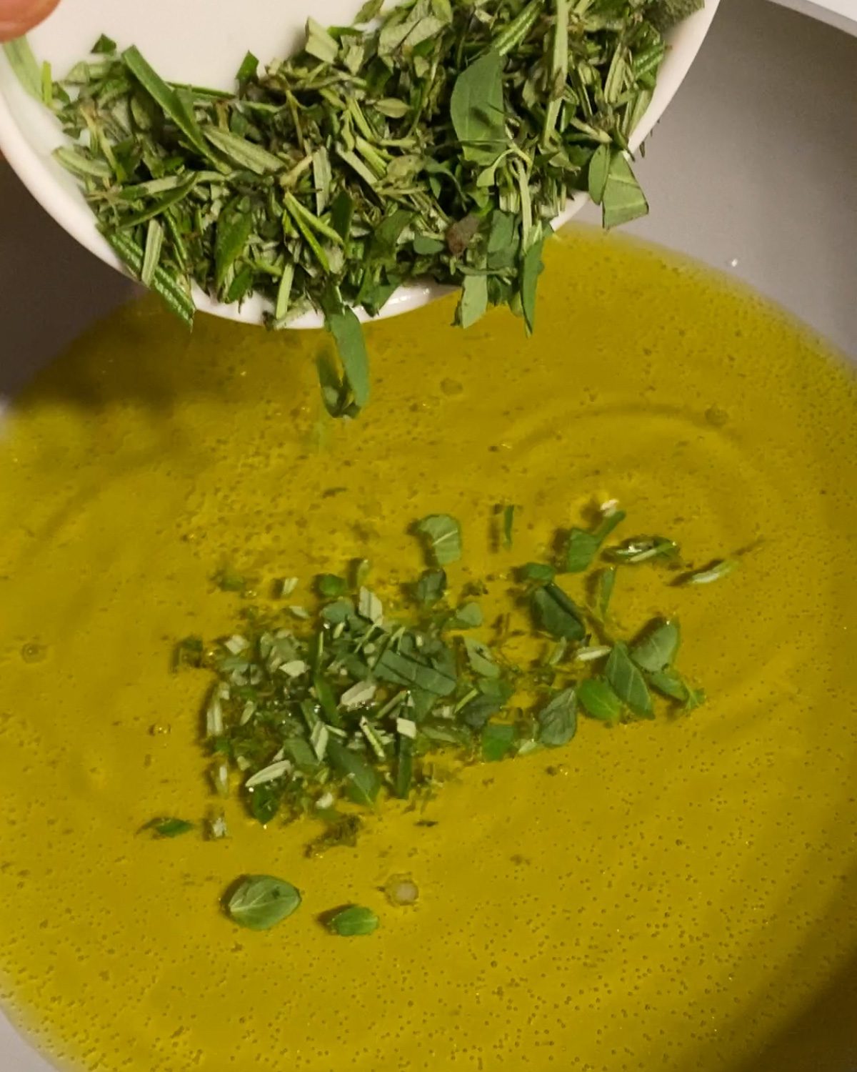 process of pouring herbs into a pan