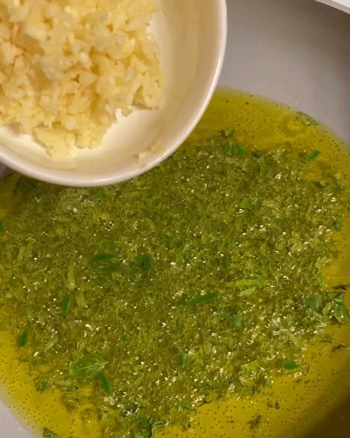process of pouring garlic into a pan