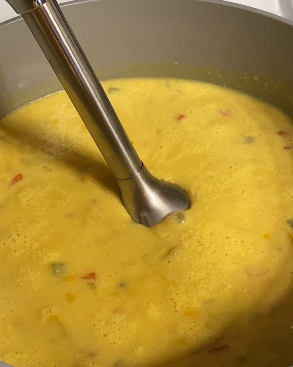 Process of using immersion blender in chowder mixture in pan.
