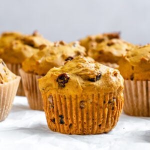 several completed Easy Vegan Pumpkin Muffins on a white surface