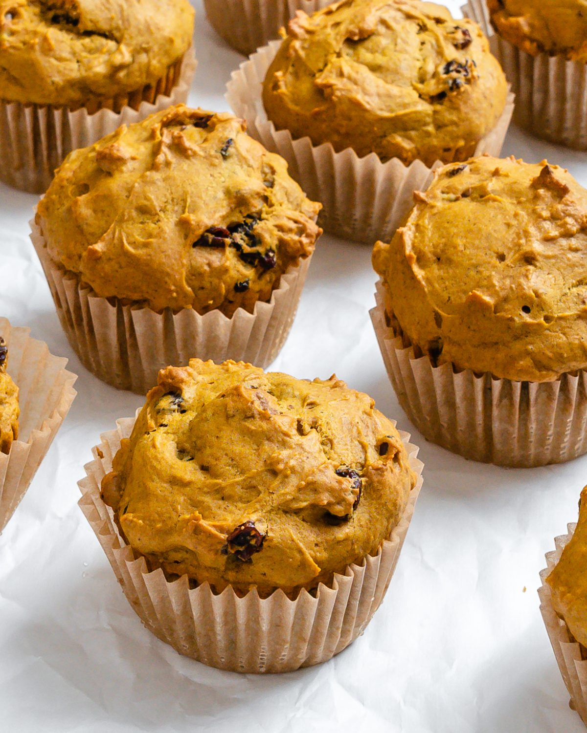 several completed Easy Vegan Pumpkin Muffins on a white surface