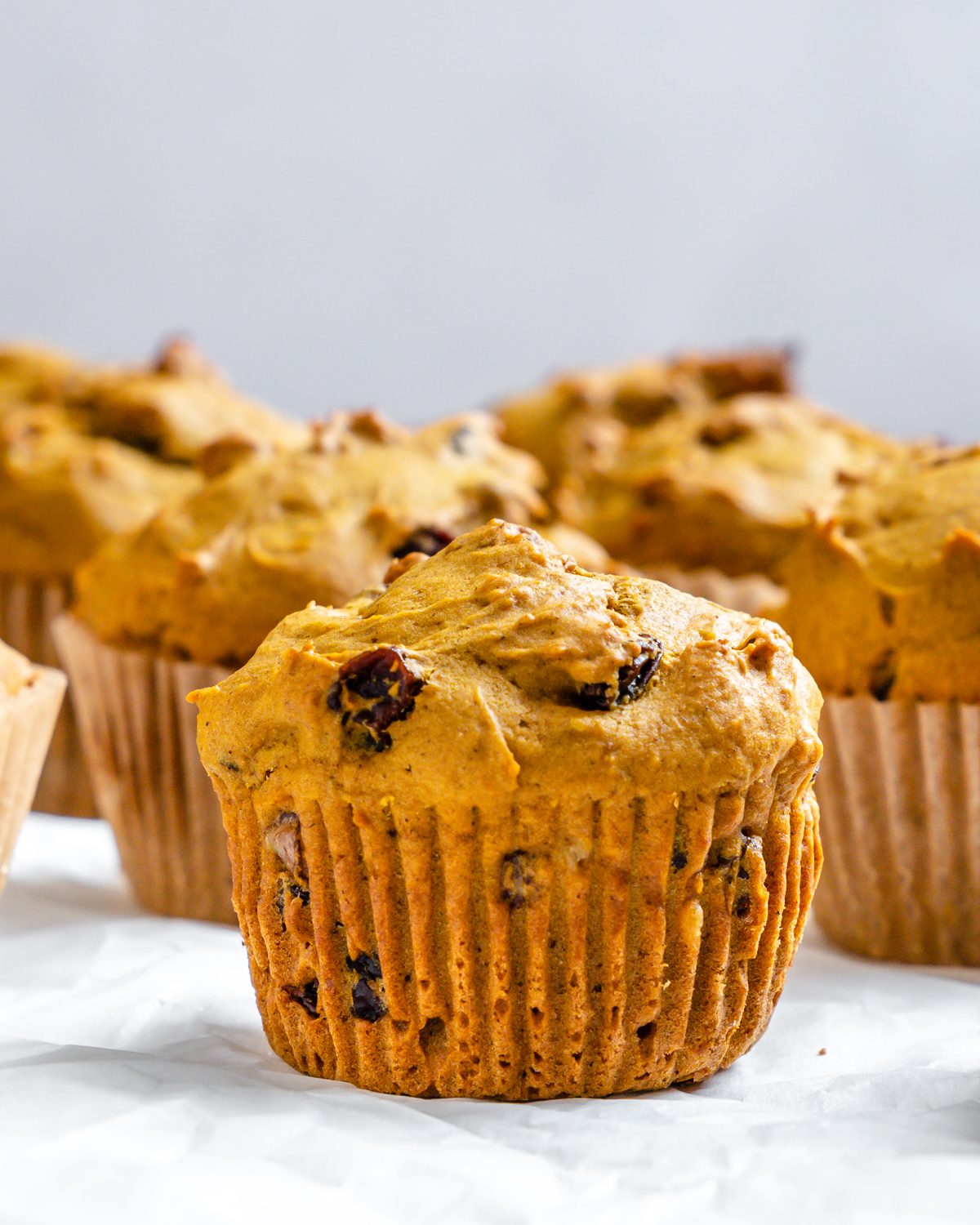 several completed Easy Vegan Pumpkin Muffins on a white surface