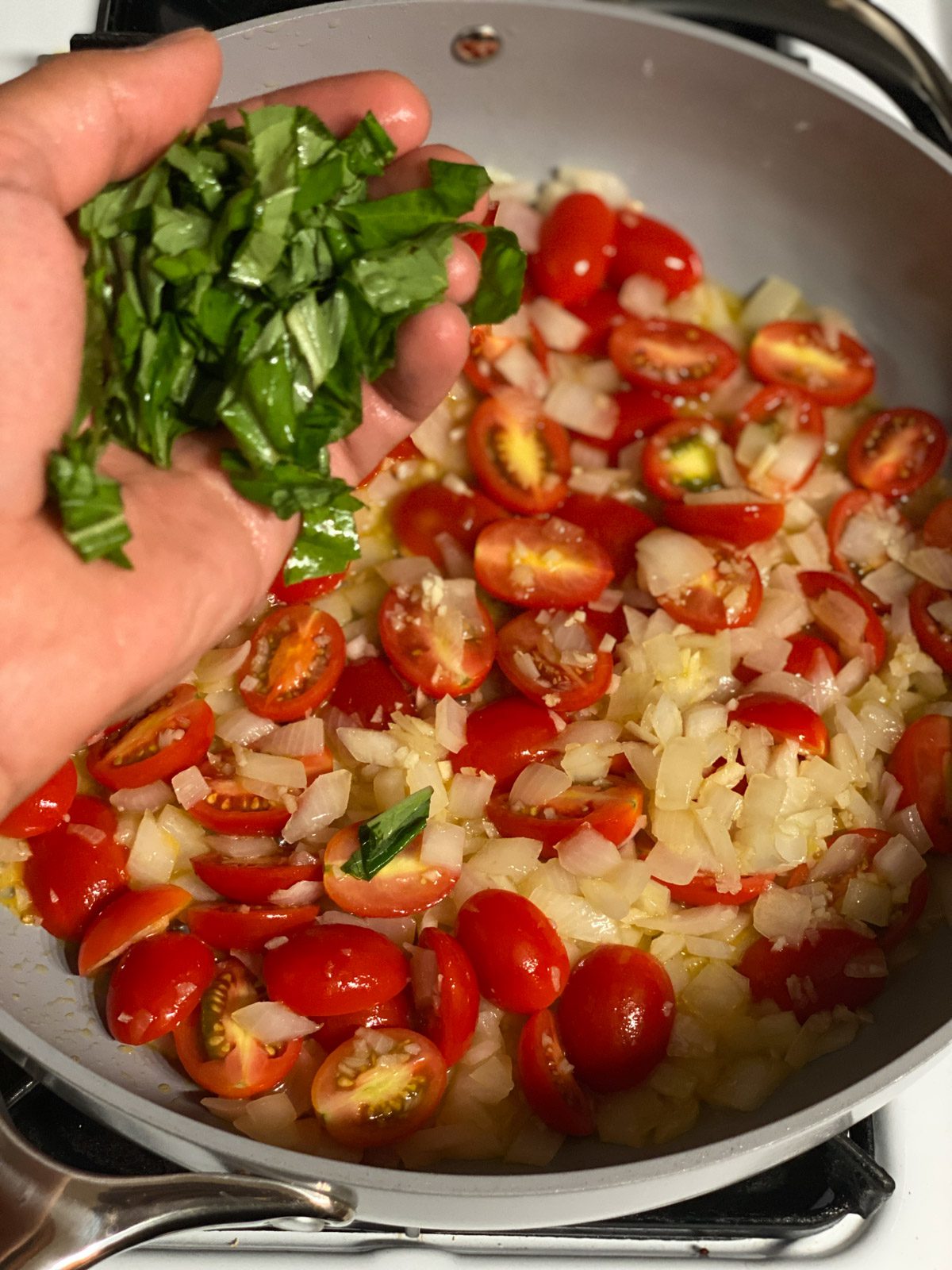 Process shot of adding basil to pan.