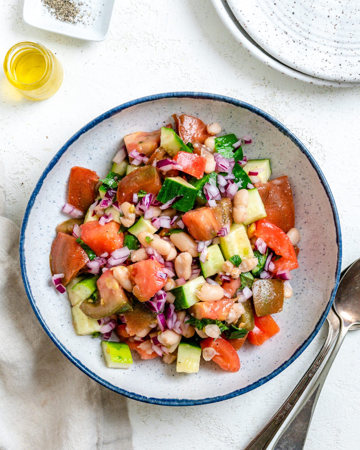 Completed Easy Mediterranean White Bean Salad in a bowl alongside utensils.