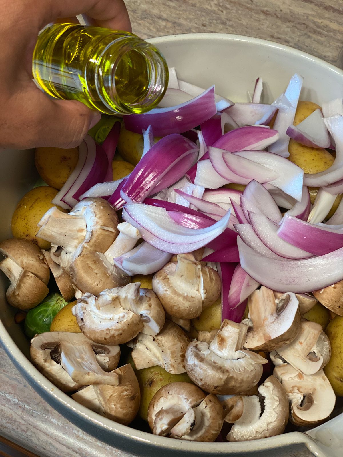 process shot of pouring oil into bowl of veggies