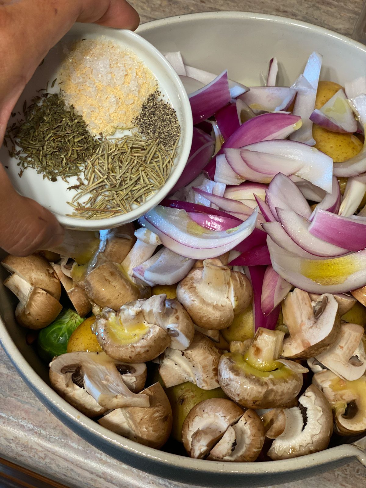 process shot of pouring seasonings for Roasted Vegetables in a bowl