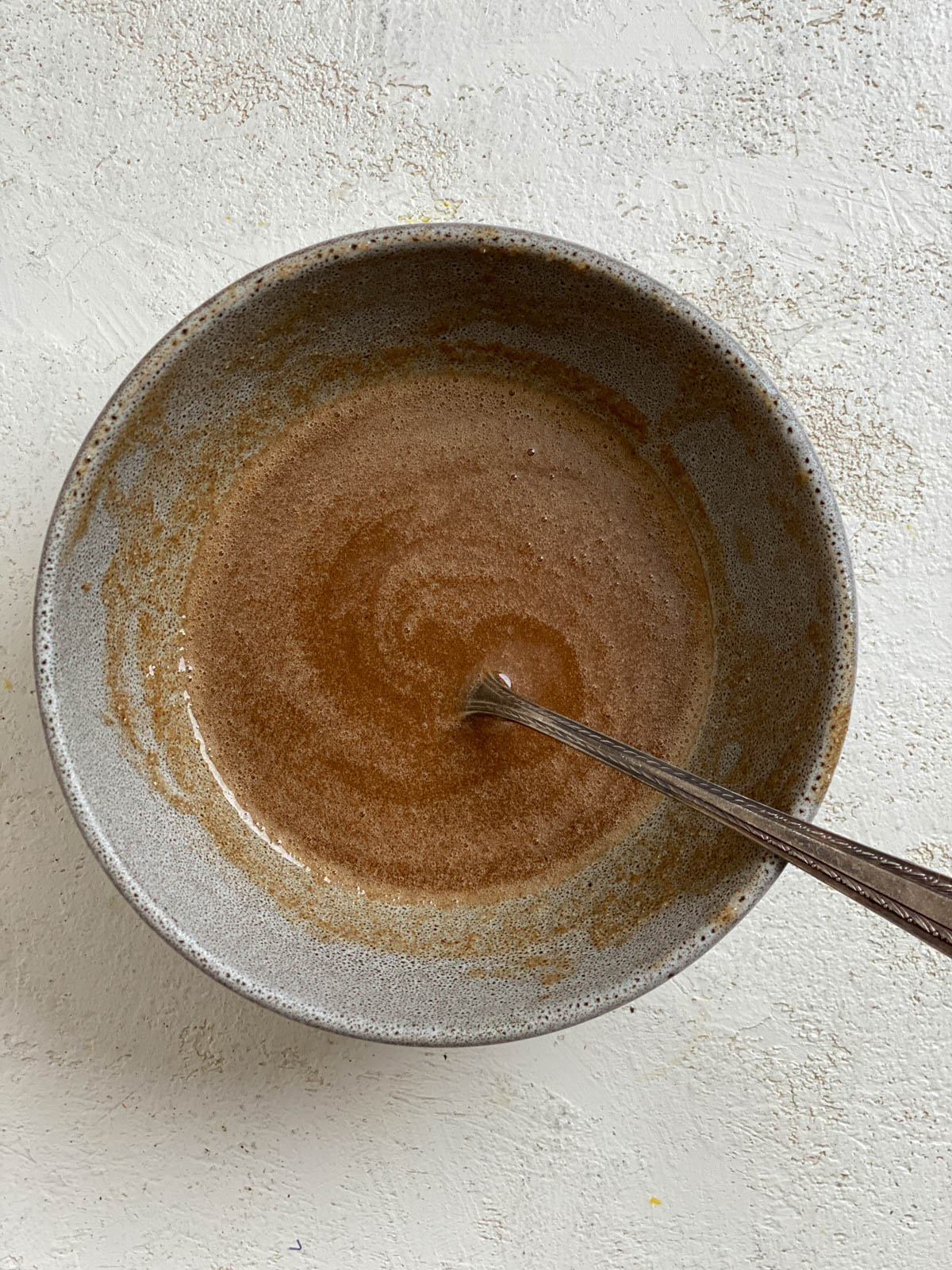 process shot of mixing candied liquid for candied yams in a bowl against a white surface