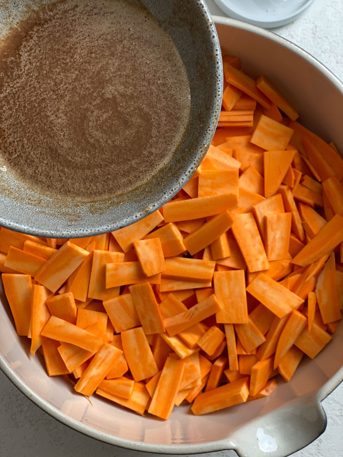process shot of adding candied liquid to yams in a bowl