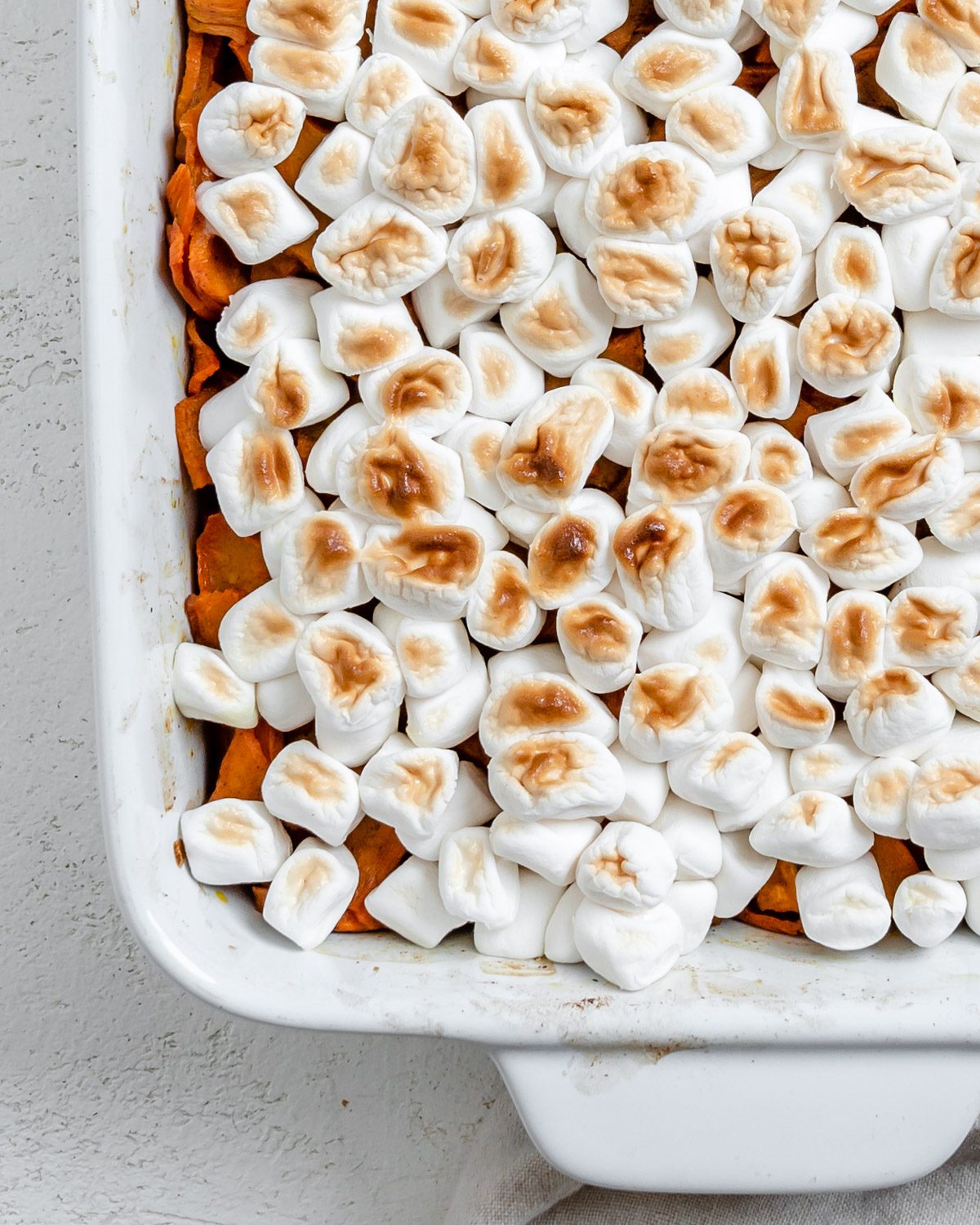completed Vegan Candied Yams with Marshmallows in a baking dish against a white background