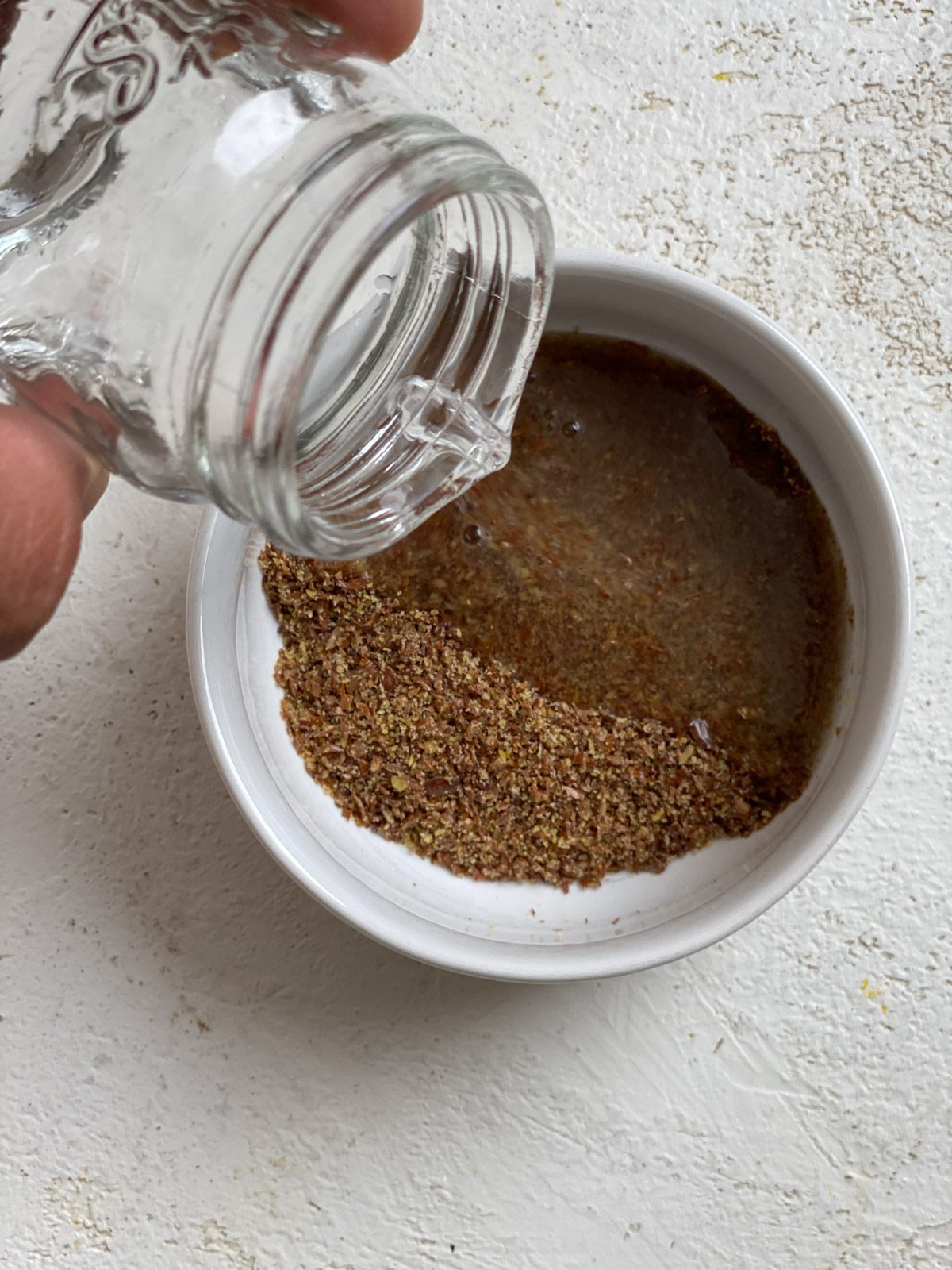 process shot of pouring water into bowl of flaxseed against a white surface