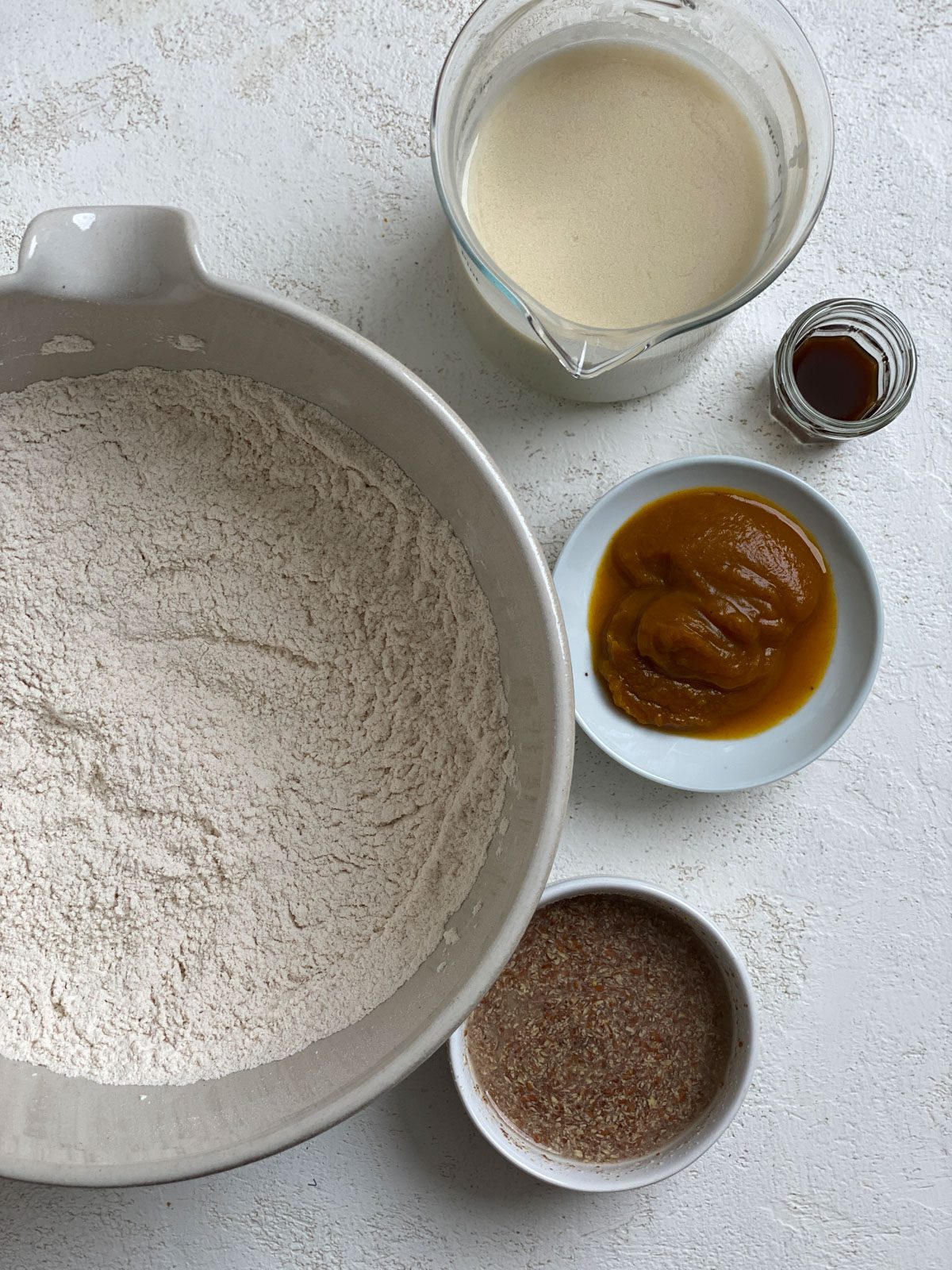 ingredients for Vegan Pumpkin Pancakes alongside a bowl of flour