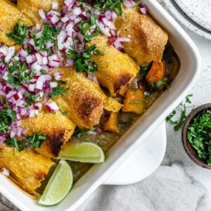 completed Easy Butternut Squash Enchiladas in a baking tray against a white background