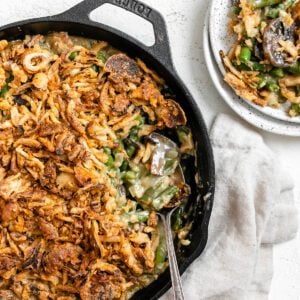 completed Dairy-Free Green Bean Casserole in a skillet with a portion plated on a white plate