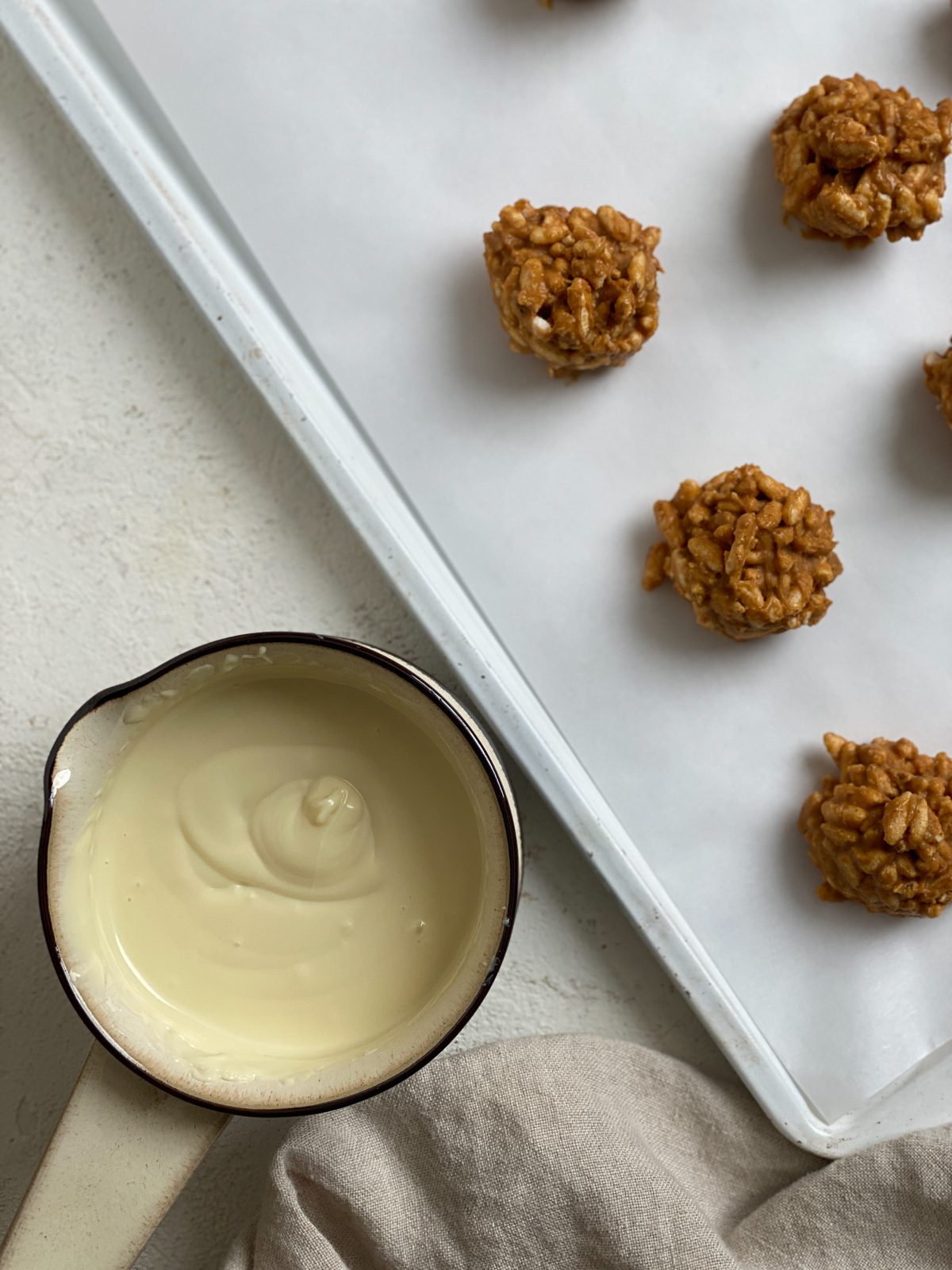 process shot of small cookie balls on a baking sheet with small bowl of dip alongside tray