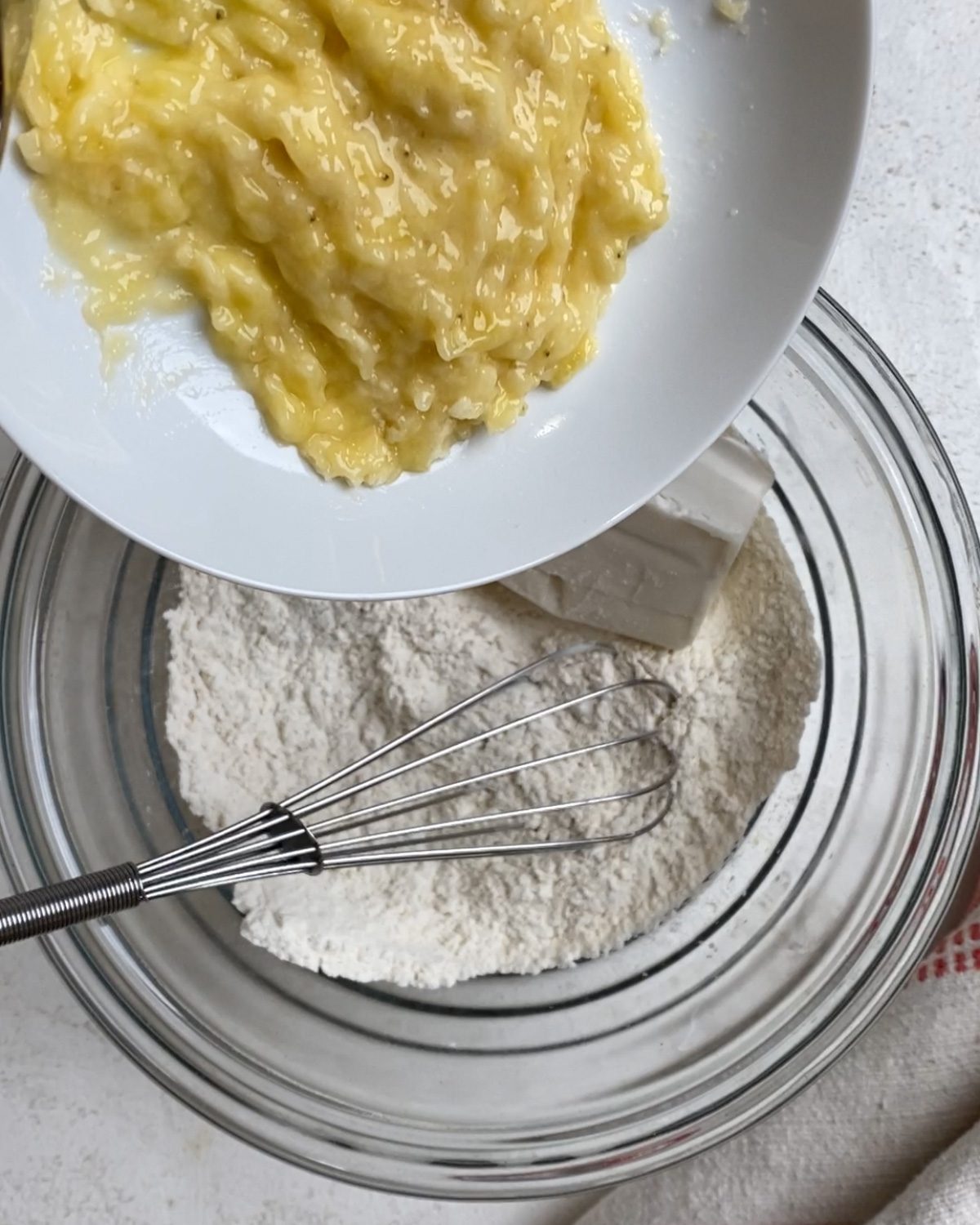 process of adding mashed bananas to bowl
