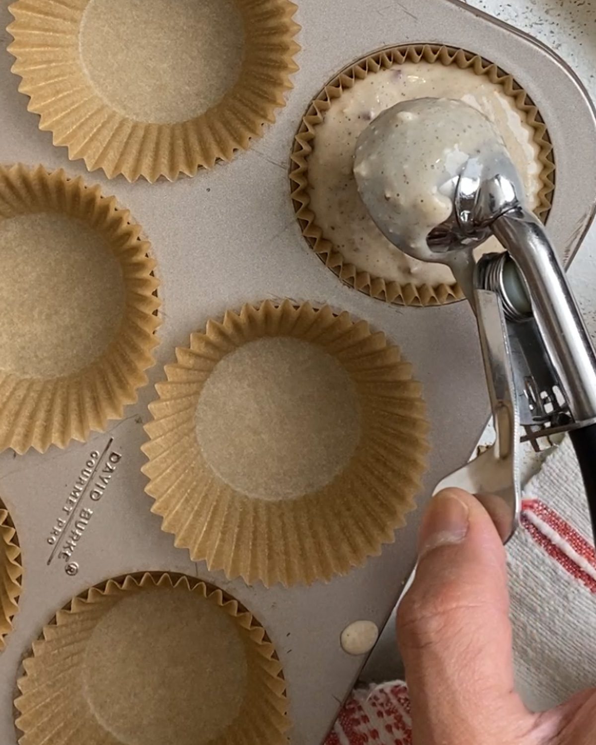 process shot of adding muffin batter to muffin tin