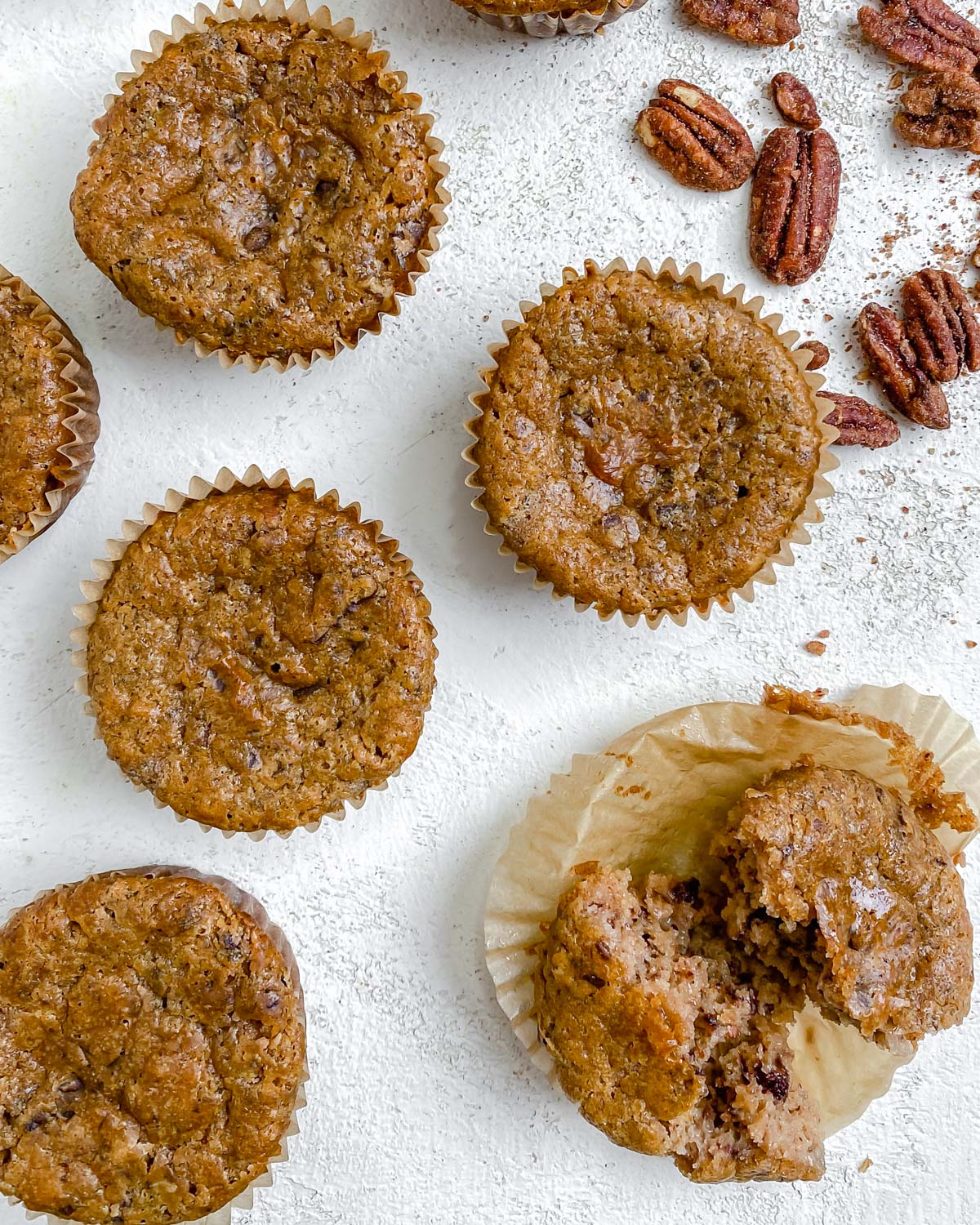 completed Vegan Cinnamon and Banana Pecan Muffins scattered on a white surface