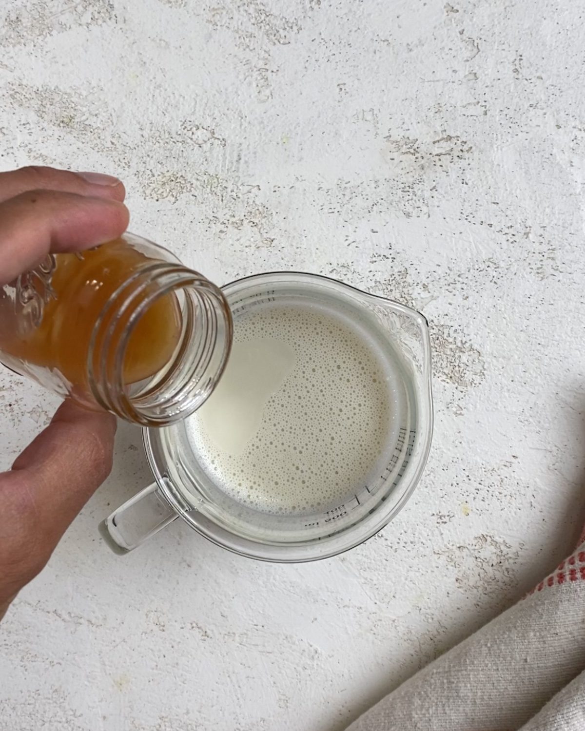 process of adding milk and vinegar to glass bowl
